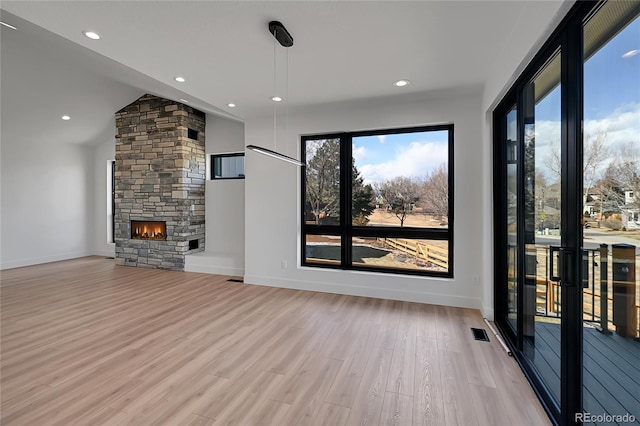 804 Spyglass Cir, Louisville, CO 80027 - unfurnished living room featuring a stone fireplace, light wood-style flooring, recessed lighting, lofted ceiling, and visible vents