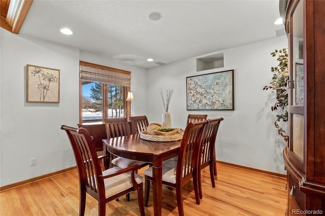 dining area with light hardwood / wood-style flooring and a textured ceiling