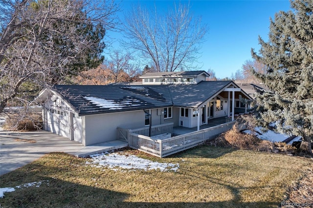 view of front of home featuring a wooden deck, a garage, and a front lawn