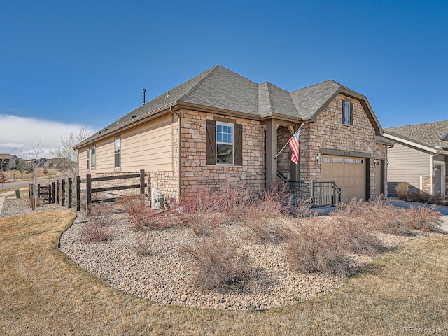 view of front of home with stone siding, a shingled roof, a garage, and fence