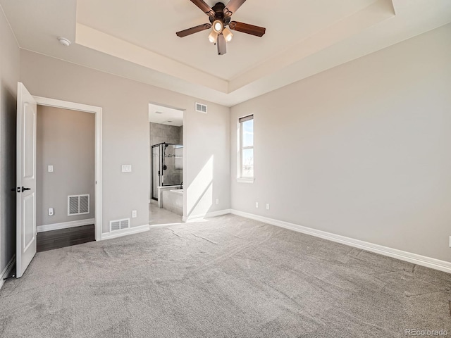 unfurnished bedroom featuring visible vents, carpet, a raised ceiling, and baseboards