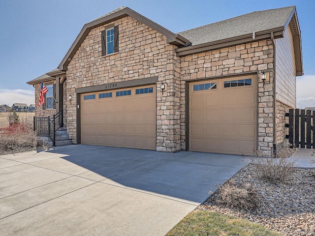 view of front of property featuring an attached garage, stone siding, driveway, and a shingled roof