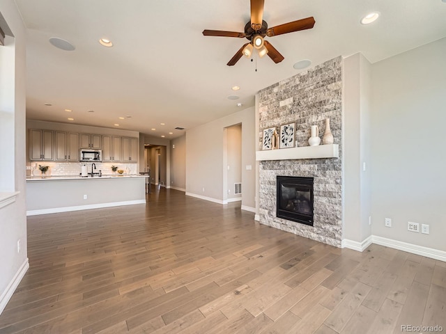 unfurnished living room with recessed lighting, baseboards, wood finished floors, and a fireplace