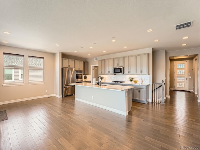 kitchen featuring visible vents, gray cabinetry, dark wood finished floors, stainless steel appliances, and a sink