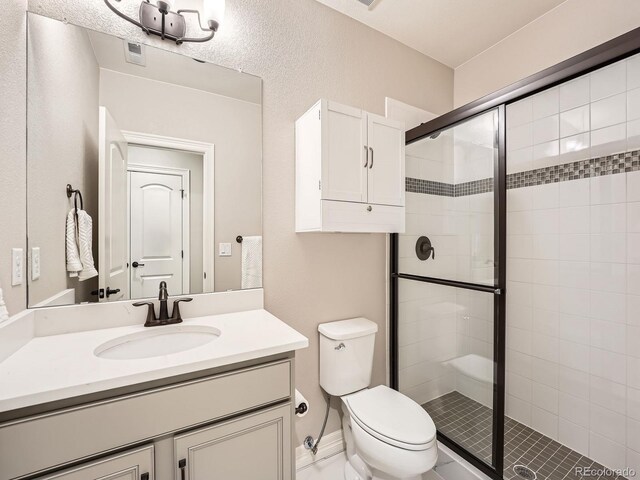 bathroom featuring visible vents, toilet, a stall shower, and vanity