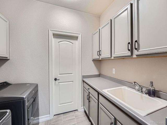 laundry room with cabinet space, washer and dryer, baseboards, and a sink