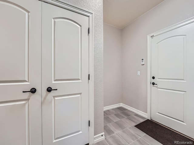 foyer entrance with baseboards and a textured wall