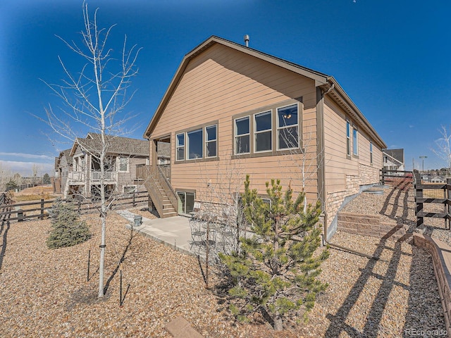 rear view of house with stairway, a patio area, and fence