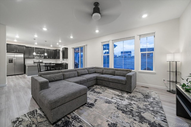 living room featuring ceiling fan, a water view, and light wood-type flooring