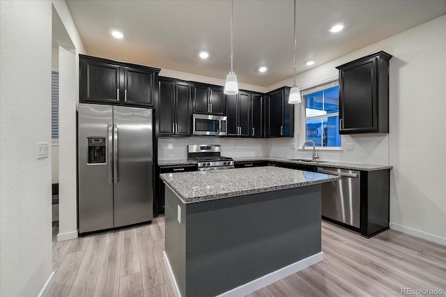 kitchen with a center island, light hardwood / wood-style flooring, light stone countertops, decorative light fixtures, and stainless steel appliances