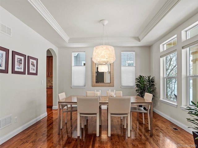 dining room featuring dark hardwood / wood-style floors, crown molding, and a tray ceiling