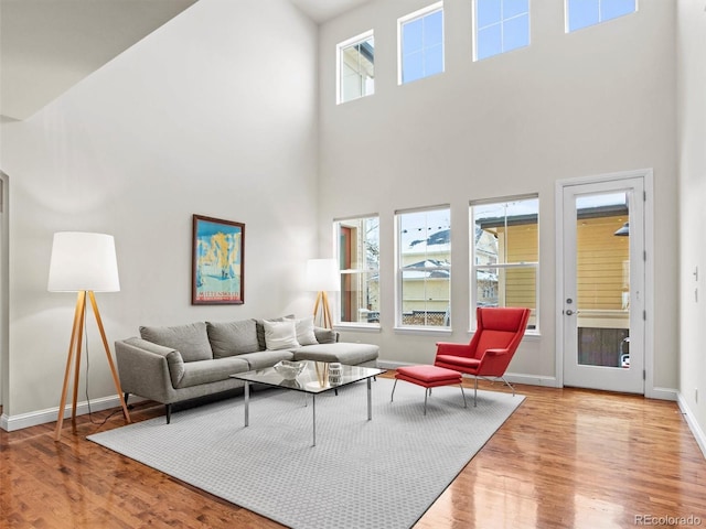 living room featuring light hardwood / wood-style floors, a towering ceiling, and a wealth of natural light