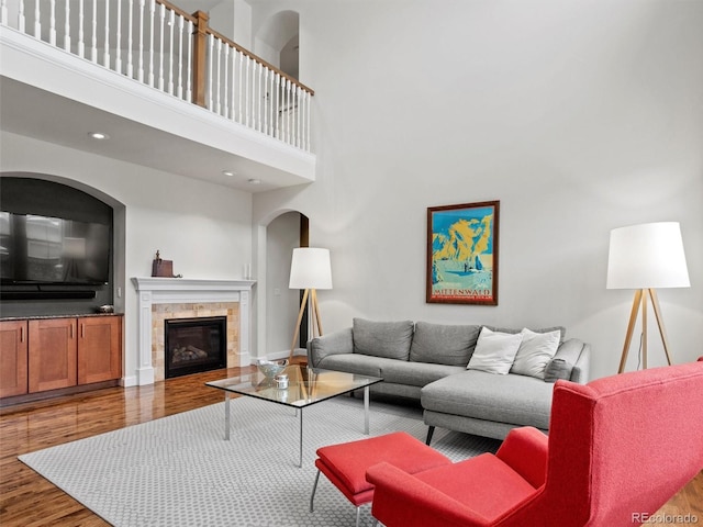 living room featuring hardwood / wood-style flooring, a fireplace, and a high ceiling