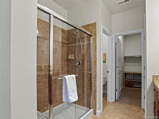 bathroom with tile patterned flooring, vanity, toilet, and a shower with shower door