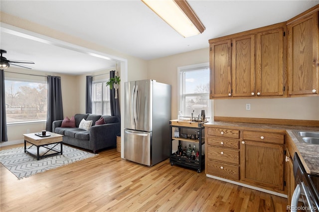 kitchen with ceiling fan, sink, light wood-type flooring, and stainless steel appliances