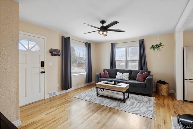 living room with ceiling fan, light hardwood / wood-style floors, and plenty of natural light