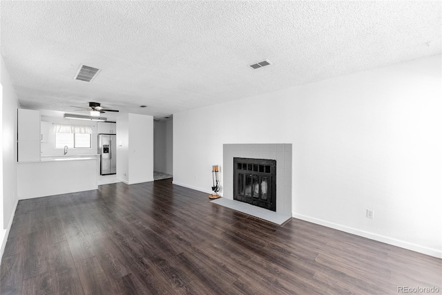 unfurnished living room with a textured ceiling, dark hardwood / wood-style flooring, and ceiling fan