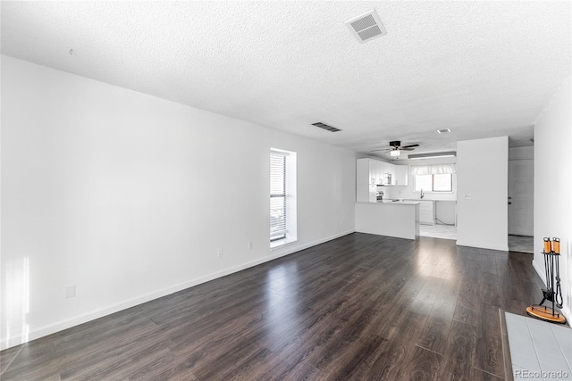 unfurnished living room featuring a textured ceiling, dark hardwood / wood-style floors, and ceiling fan