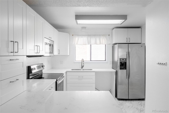 kitchen featuring white cabinets, sink, stainless steel appliances, and a textured ceiling