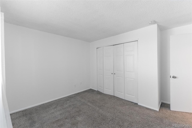 unfurnished bedroom featuring dark colored carpet, a textured ceiling, and a closet