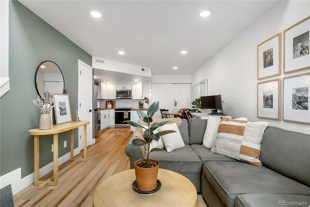 living area featuring light wood-style floors, baseboards, visible vents, and recessed lighting
