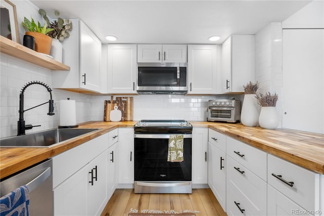 kitchen with open shelves, a sink, wooden counters, appliances with stainless steel finishes, and a toaster
