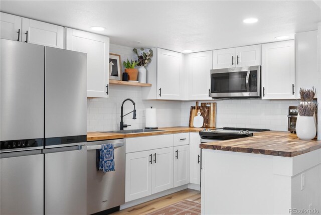 kitchen featuring wooden counters, a sink, open shelves, and appliances with stainless steel finishes