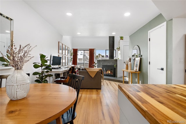 dining room with light wood-style flooring, recessed lighting, and a glass covered fireplace