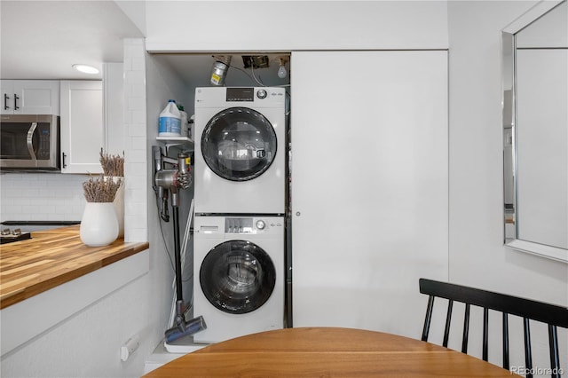clothes washing area featuring stacked washer and clothes dryer and laundry area