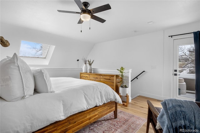 bedroom with access to outside, baseboards, light wood-type flooring, a ceiling fan, and a skylight