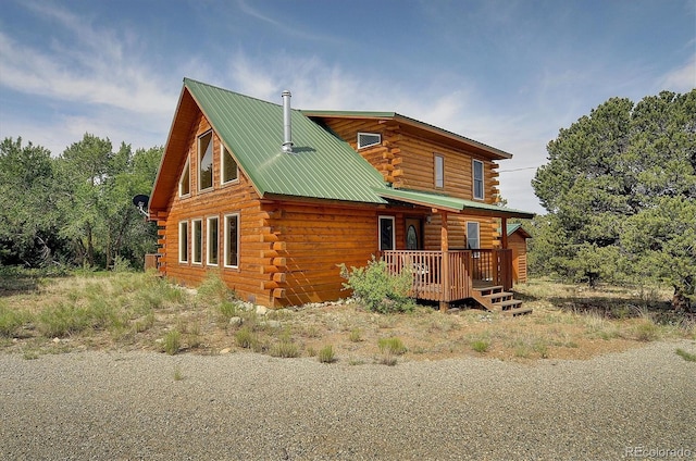 log cabin with metal roof, a porch, and log exterior