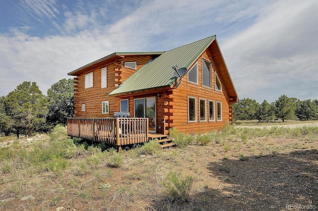 rear view of house with a wooden deck, log exterior, and metal roof