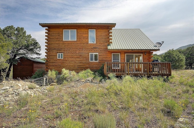 rear view of property featuring a deck, log exterior, and metal roof