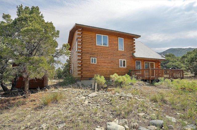 rear view of property featuring log exterior and a deck with mountain view