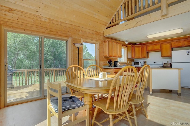 dining area featuring high vaulted ceiling, wood walls, wood ceiling, and light wood-style floors