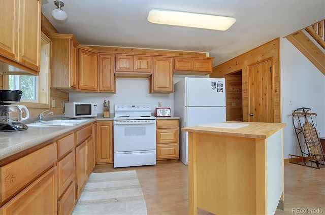 kitchen featuring white appliances, butcher block countertops, light brown cabinetry, a sink, and light wood-type flooring