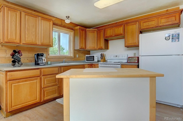 kitchen featuring white appliances, a kitchen island, a sink, light countertops, and light wood-type flooring