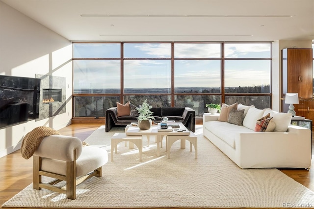 living room with expansive windows, a high end fireplace, and hardwood / wood-style floors