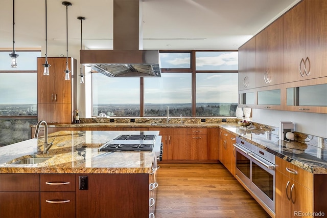 kitchen featuring pendant lighting, sink, a healthy amount of sunlight, and island exhaust hood