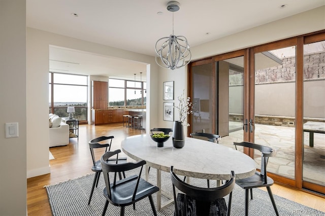 dining space with french doors, a chandelier, and light wood-type flooring