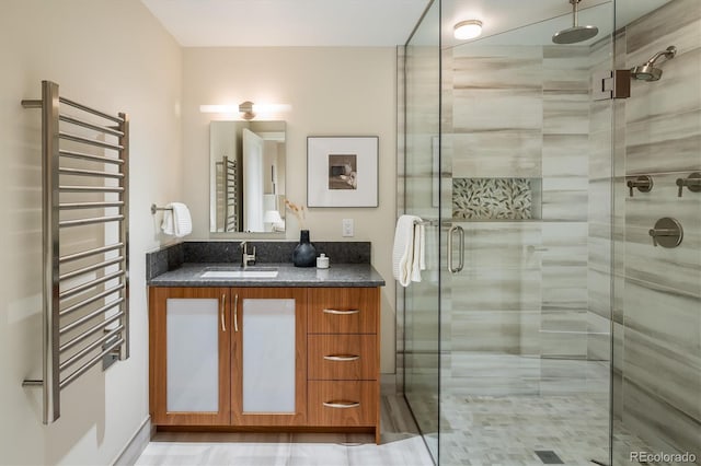 bathroom with a shower with door, vanity, and radiator