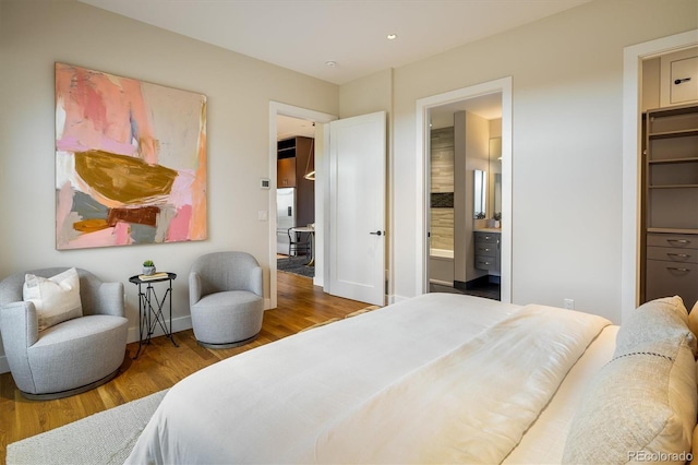 bedroom featuring a walk in closet, hardwood / wood-style floors, ensuite bath, and a closet