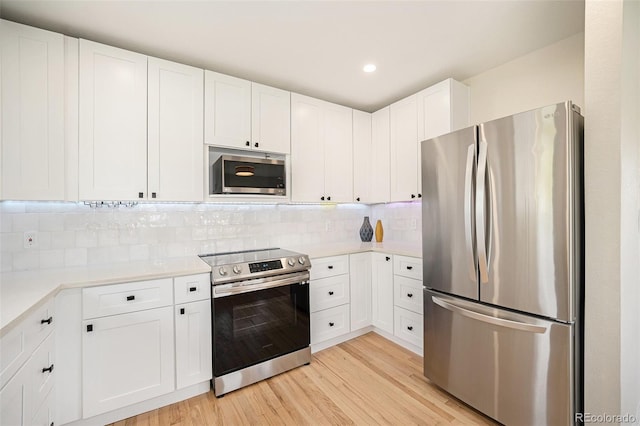 kitchen featuring white cabinetry, stainless steel appliances, light hardwood / wood-style floors, and tasteful backsplash