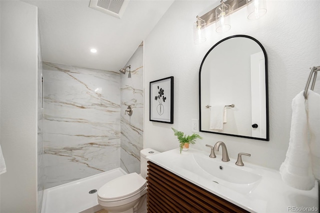 bathroom with vanity, toilet, and tiled shower