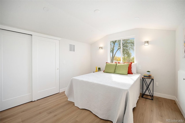 bedroom featuring a closet, lofted ceiling, and light hardwood / wood-style flooring