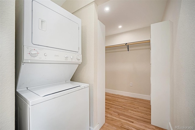 clothes washing area featuring stacked washer / dryer and light hardwood / wood-style flooring