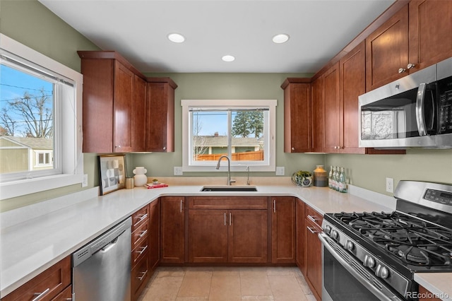 kitchen with a healthy amount of sunlight, stainless steel appliances, sink, and light tile patterned floors