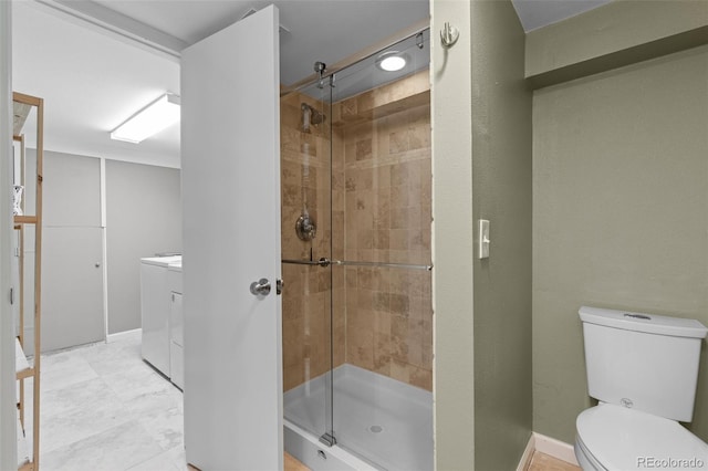 bathroom featuring vanity, washing machine and clothes dryer, an enclosed shower, and toilet