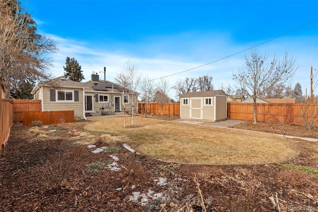 back of house featuring a storage shed, a yard, and solar panels