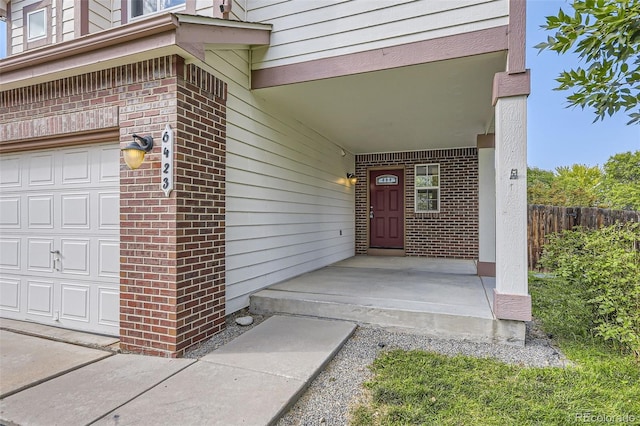 view of exterior entry featuring a porch and a garage